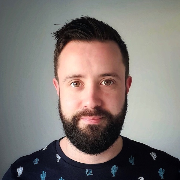 Portrait picture of me in a patterned dark blue t shirt in front of a grey background