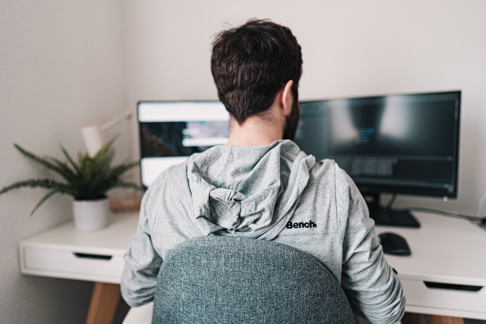 Man in grey hoodie working at a desk in a home office